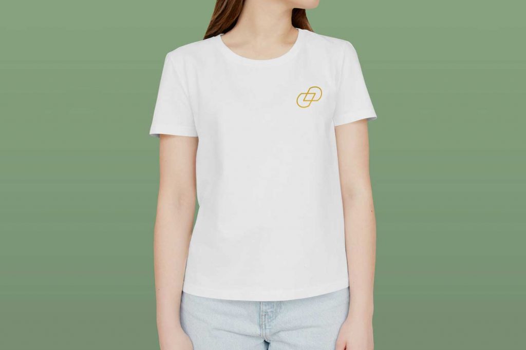Frau T-Shirt vor einem grünen Hintergrund. Sie trägt ein T-Shirt auf dem sich ein Logo befindet.